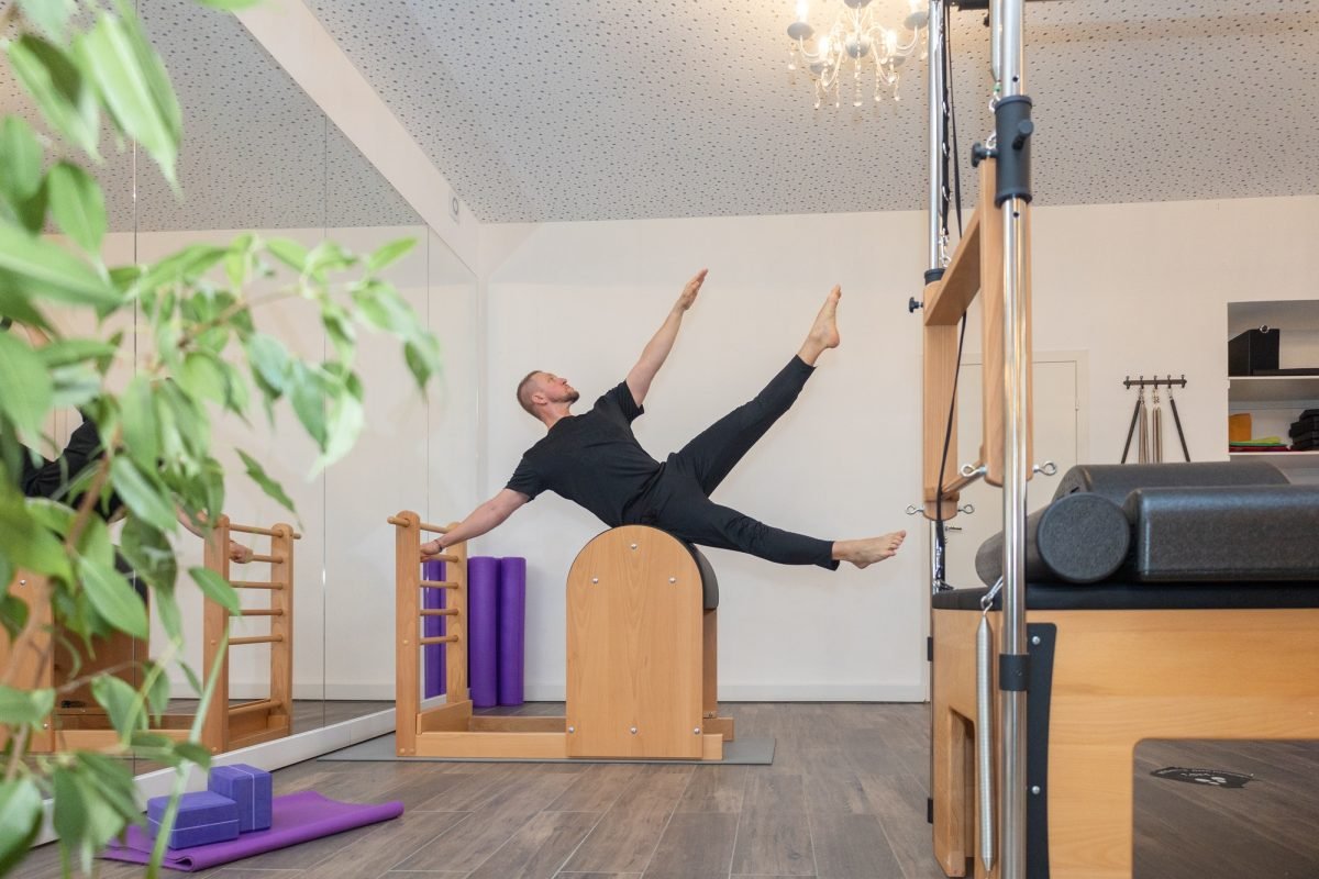 Male fitness Pilates trainer shows exercises on special simulators. Pilates Stretch Tables